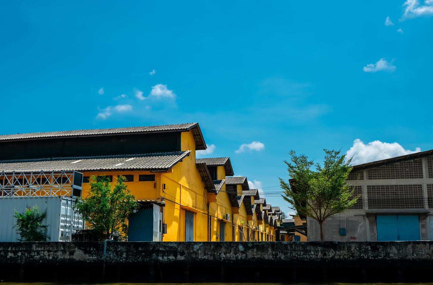 Vintage style warehouse building with blue sky and white clouds. Yellow warehouse for storage of goods. Exterior building. Vintage style architecture. Retro concrete office and warehouse building. photo