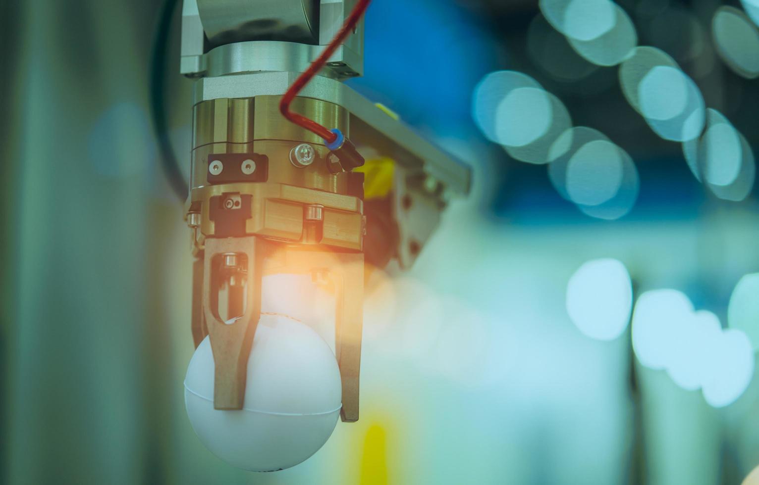 Closeup robot hand machine picking up white ball on bokeh blurred background . Use smart robot in manufacturing industry for industry 4.0 and technology concept. Robotic tool in factory. photo