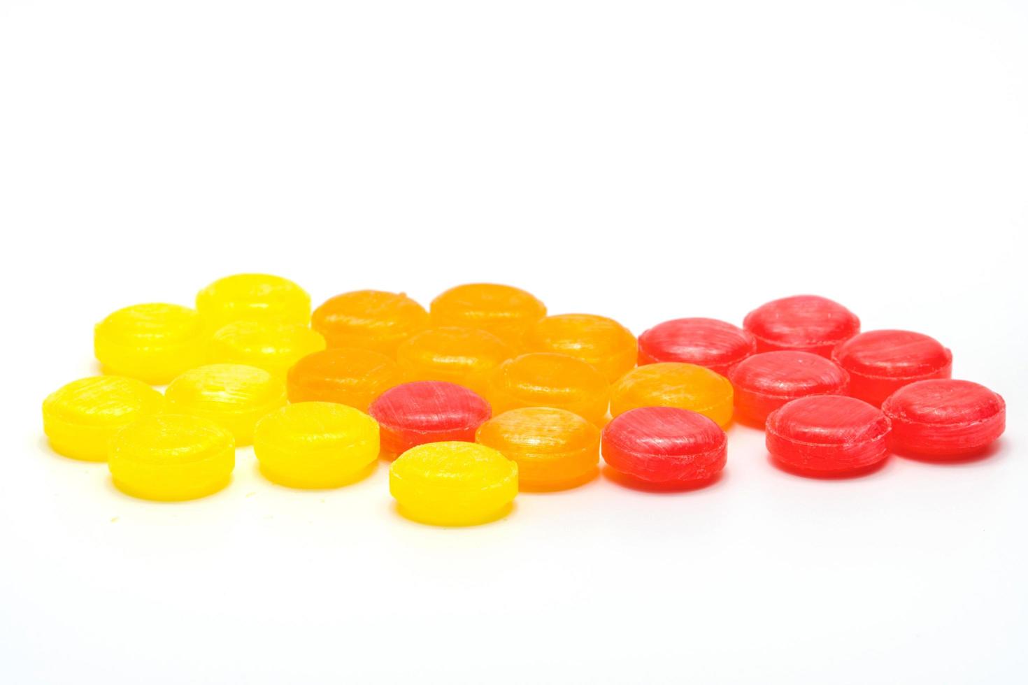 Medical lozenges for relief cough, sore throat and throat irritation isolated on white background. Cough and colds drop. Colorful cough pastille. Red, orange, and yellow round candy or sweets. photo
