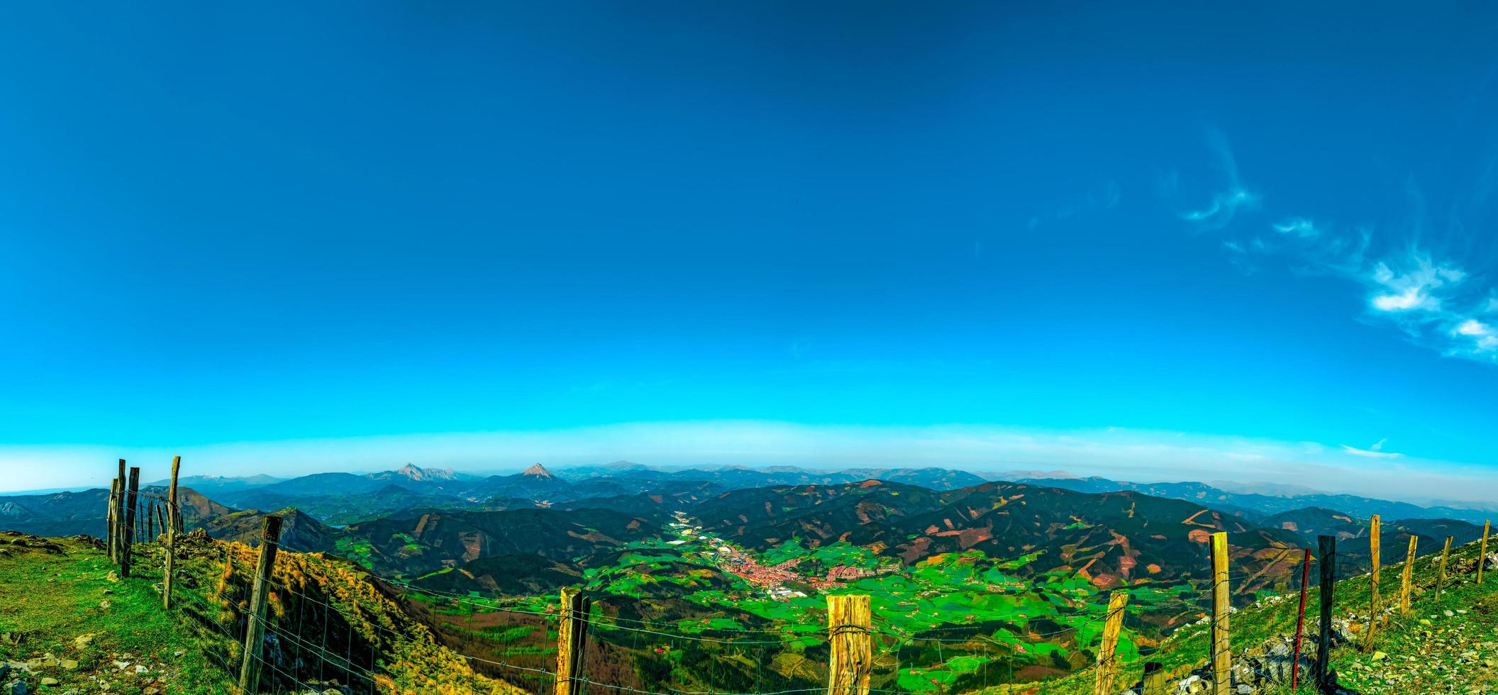 Landscape of mountain and village in valley. View from top of mountain near edge and fence. Beautiful view in Europe. Red color of home roof in valley.  Pine tree forest. Sustainable industry. photo