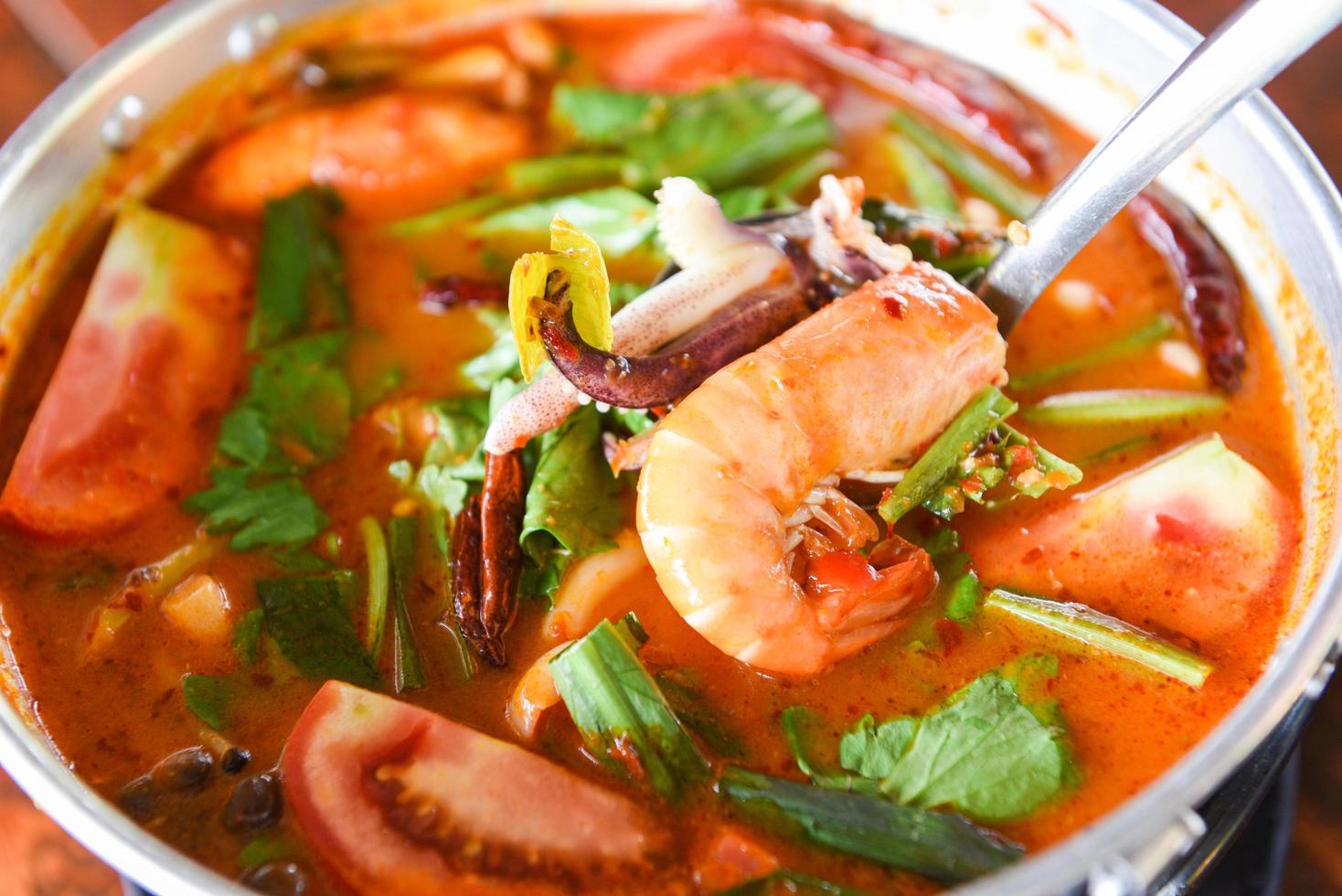 sopa de gambas, sopa picante con camarones, mariscos, leche de coco y ají en una olla, camarones al curry agridulce y calamares comida tailandesa asiática foto