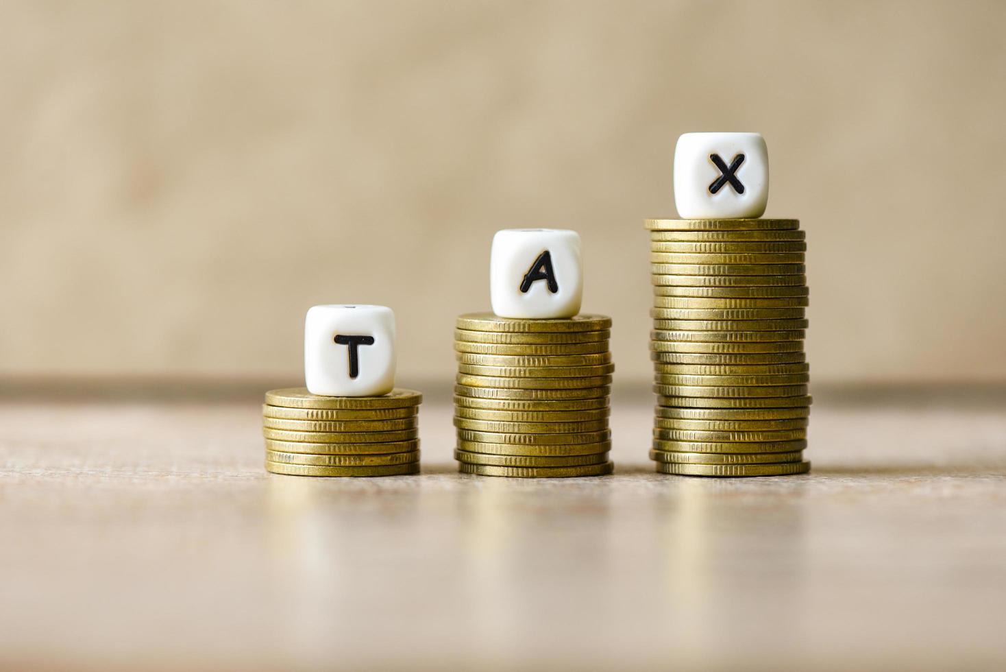 Block word tax on money on wooden background, TAX on stacked coins financial Tax concept. photo