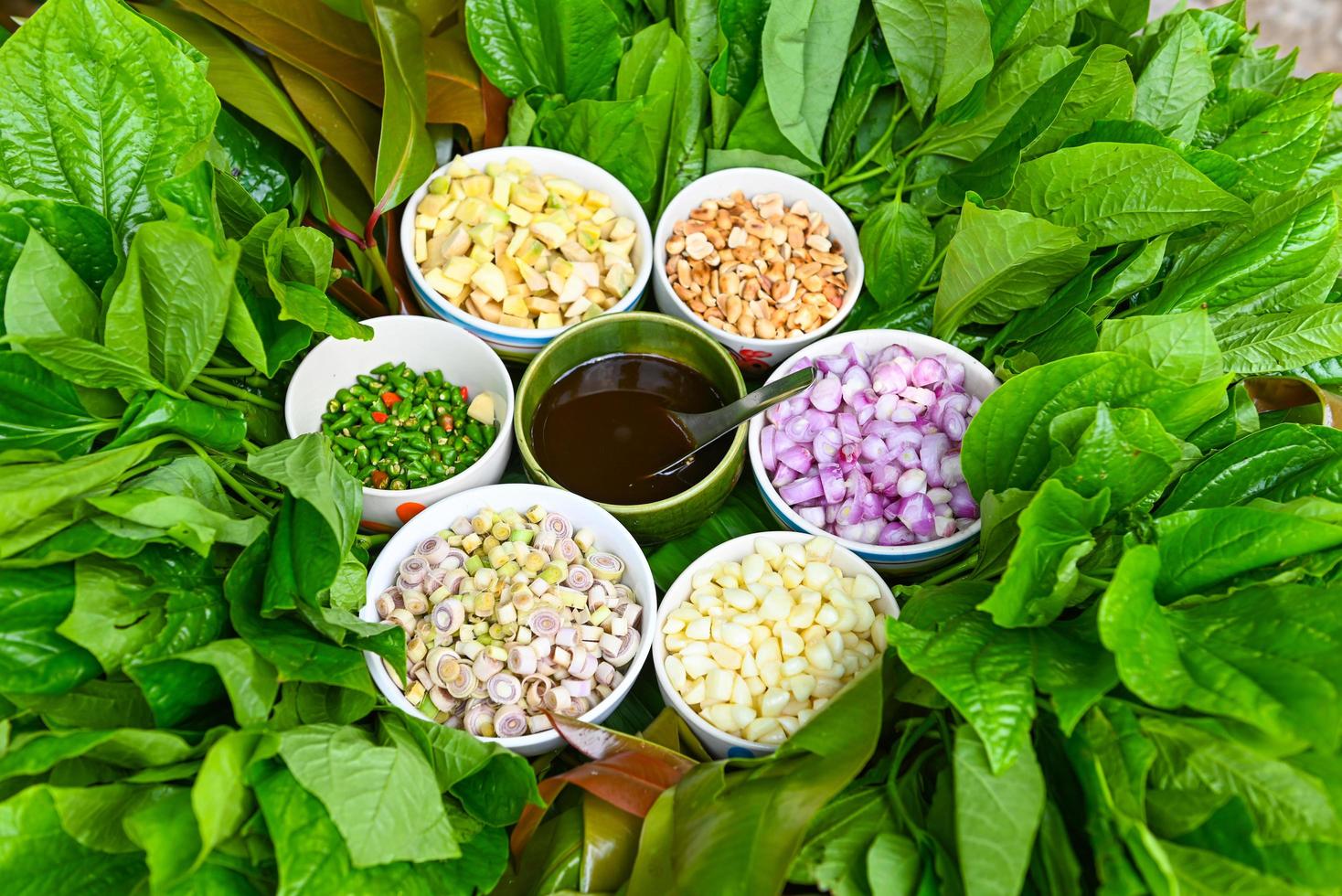 Miang Kham Or wild betel leaves wrap ingredients with lemon grass, garlic, shallot, lime, chilli, roasted peanuts with sweet dipping sauce, Asian appetizer food. photo