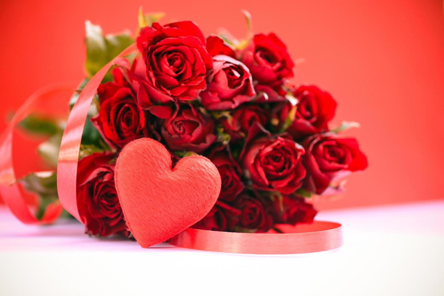 Ramo de rosas de flores sobre fondo rojo - corazón rojo con cinta y rosa amor romántico concepto de día de San Valentín foto