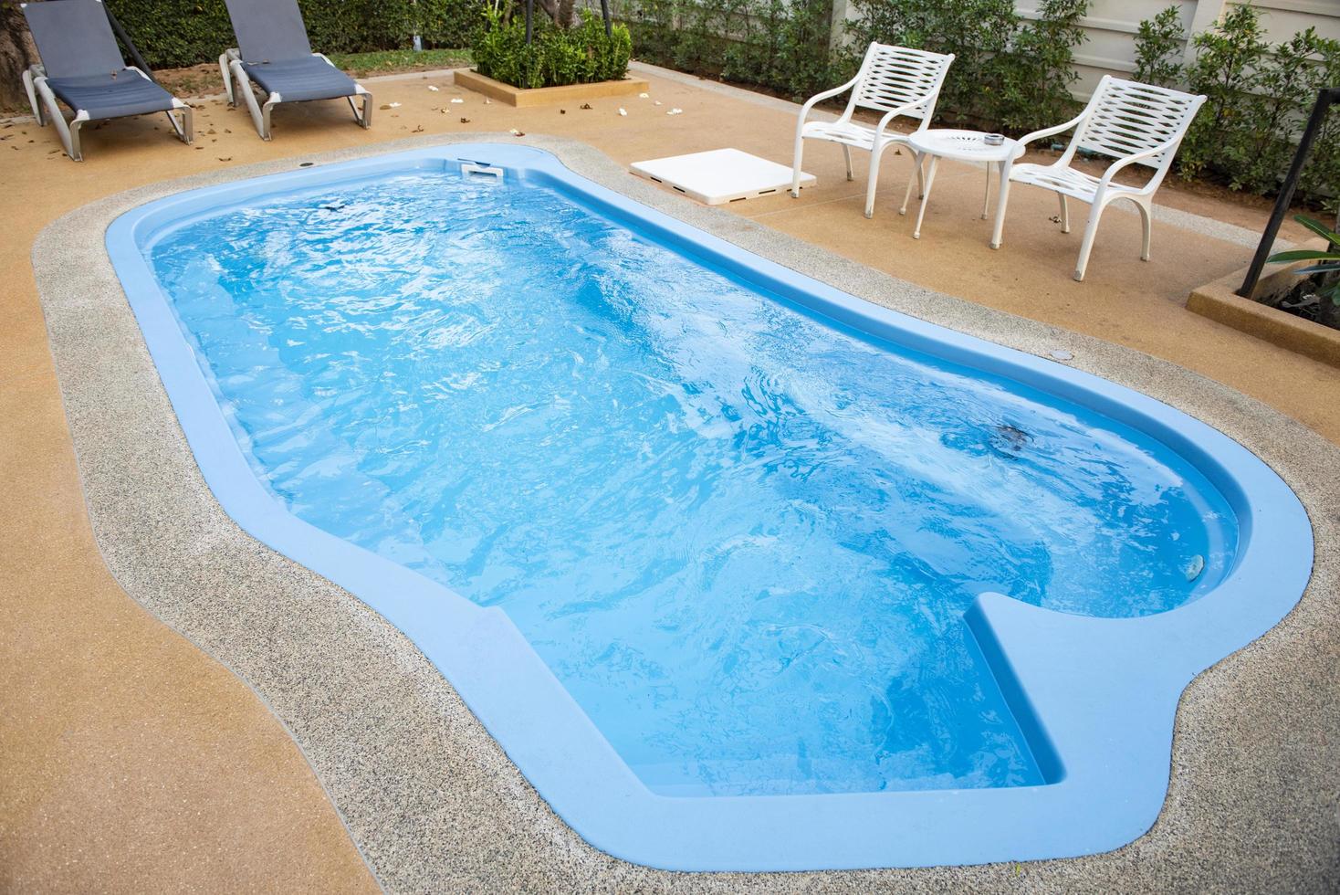 Backyard area with swimming pool blue water and tables chairs and trees fenced background , swimming pool garden photo