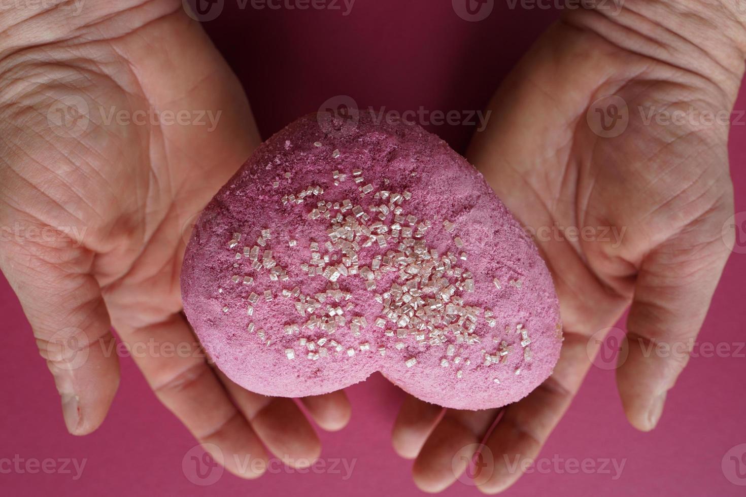 dulce corazón en la mano de la mujer. pastel para la fiesta del día de la madre. foto