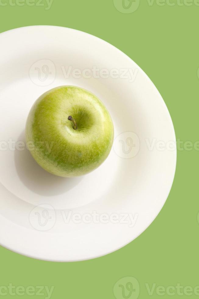 Green apple on white plate isolated on green background. photo