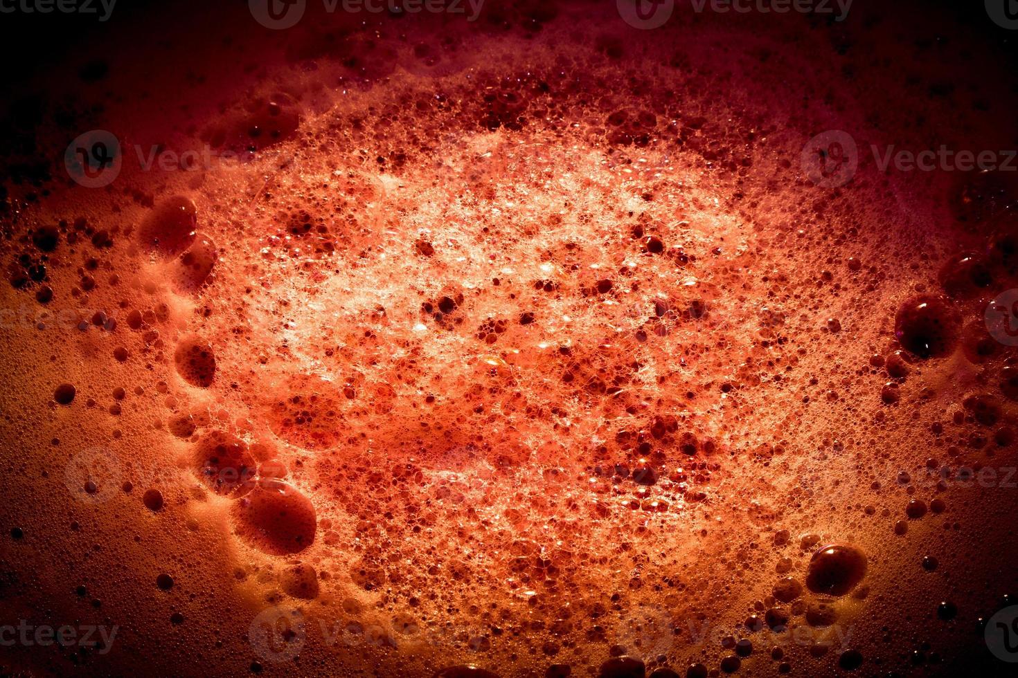 Dark red image of foam on liquid surface. Abstract red foam background. photo