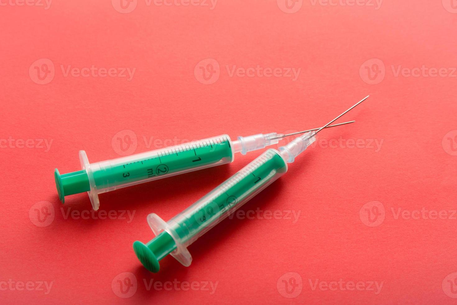 A pair of medical syringes on red background. photo