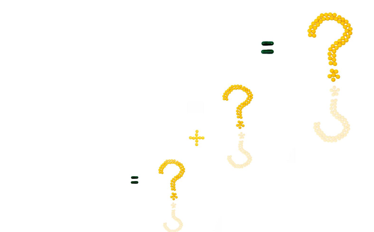 Three question mark and plus sign made of yellow sugar coated tablet pills. Equal sign made of capsule pills isolated on white background. photo
