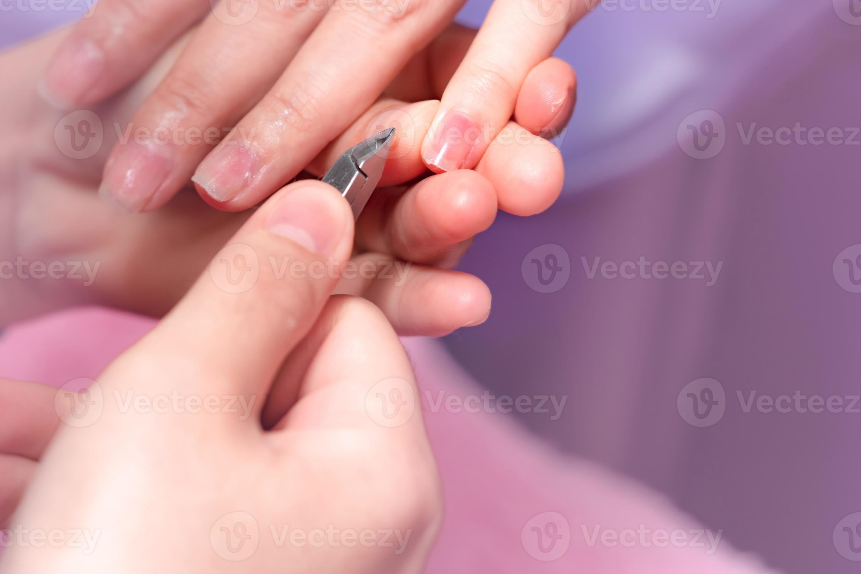 Woman receiving fingernail manicure service by professional manicurist at nail salon. Beautician