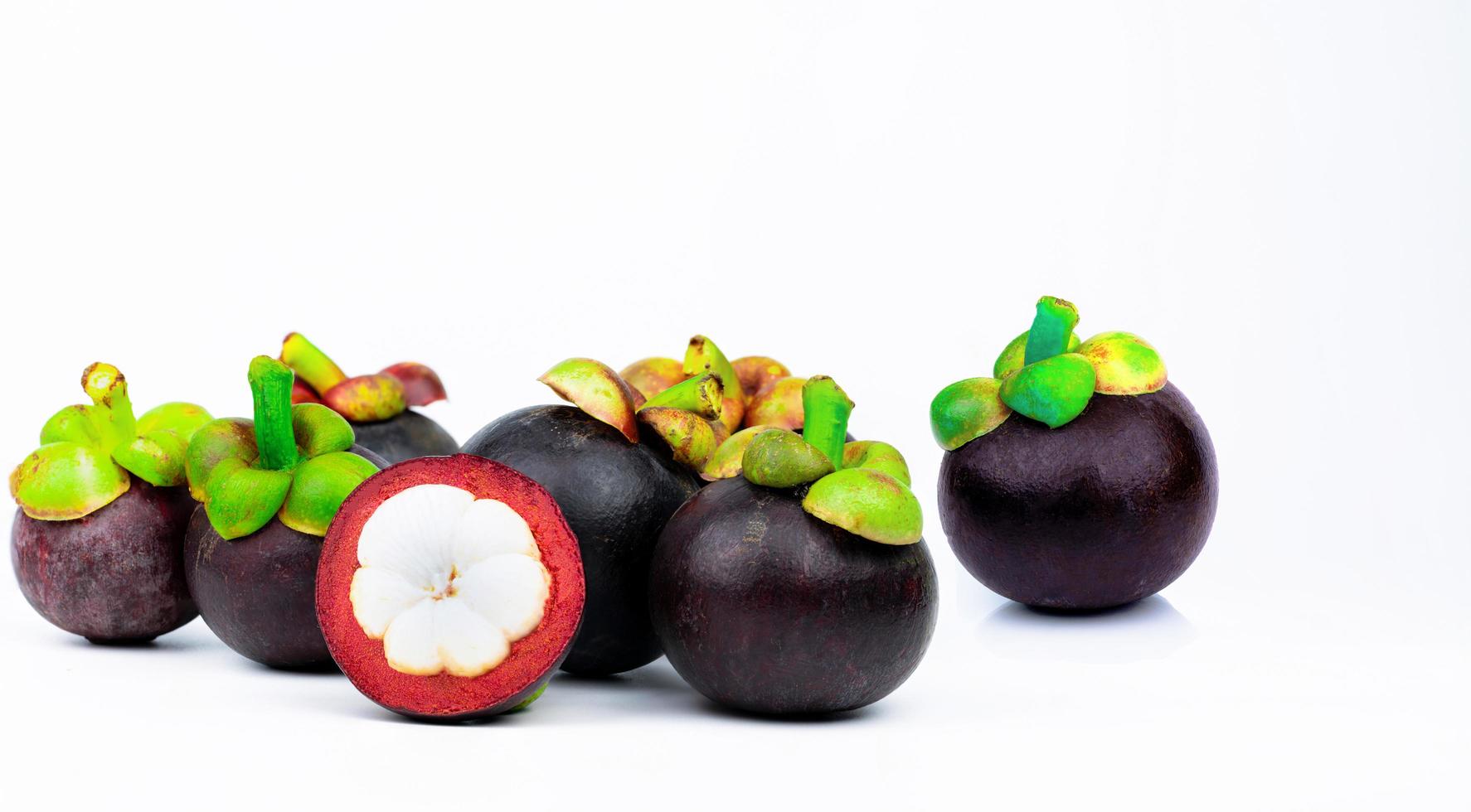 7 whole purple mangosteen and another cross section isolated on white background. Tropical fruit from Thailand. The queen of fruits. Asia fresh fruit market. Natural source of tannin and xanthones photo