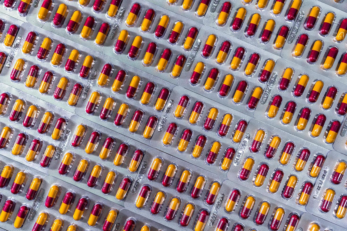 Pharmaceutical industry. Red-yellow capsule pills in blister pack. Pharmaceutical packaging. Pharmacy product. Global healthcare. Drug use in hospital. Drug market trends. Health budget and policy. photo