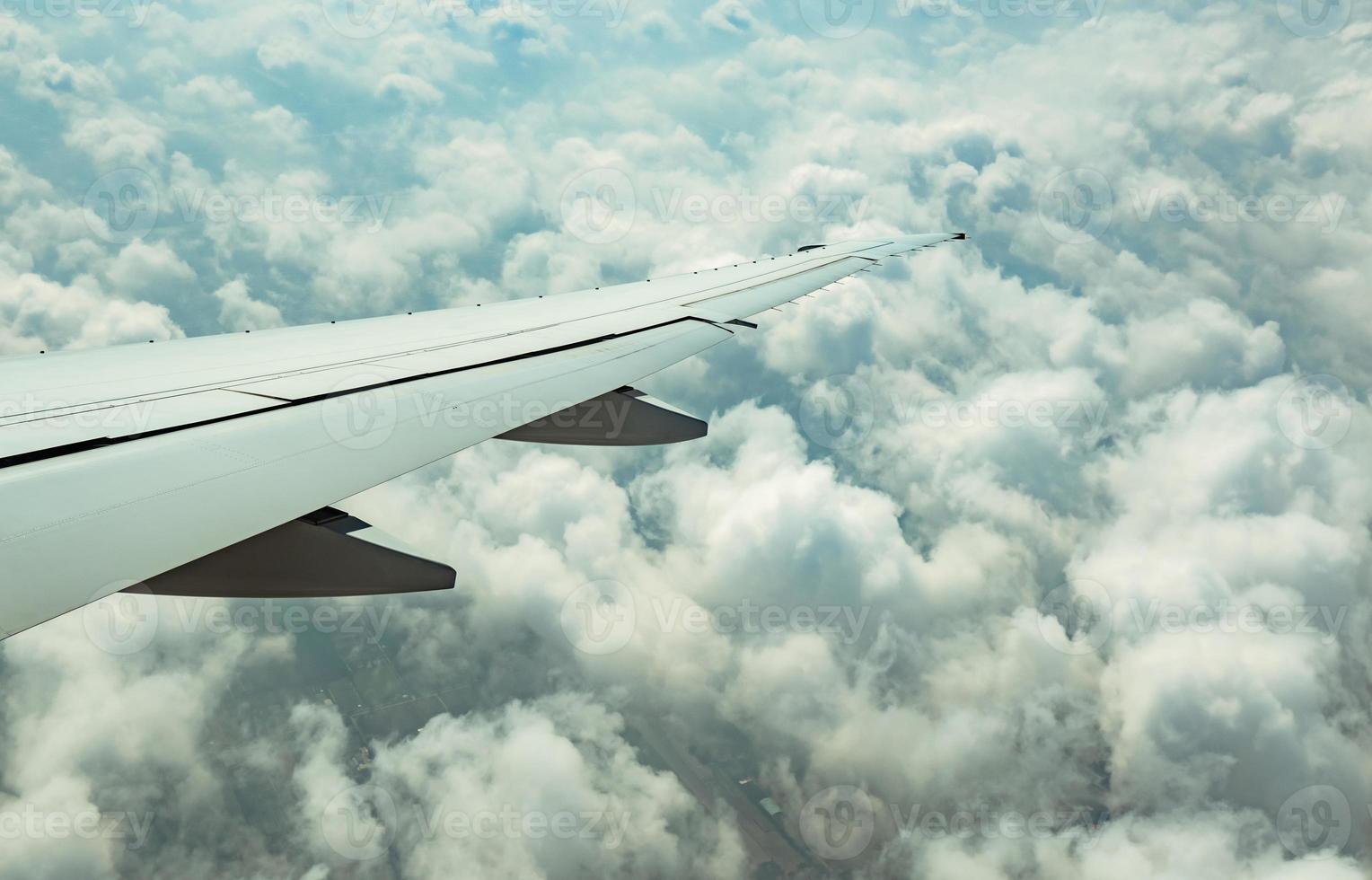 Wing of plane over white clouds. Airplane flying on blue sky. Scenic view from airplane window. Commercial airline flight. Plane wing above clouds. Flight mechanics concept. International flight. photo
