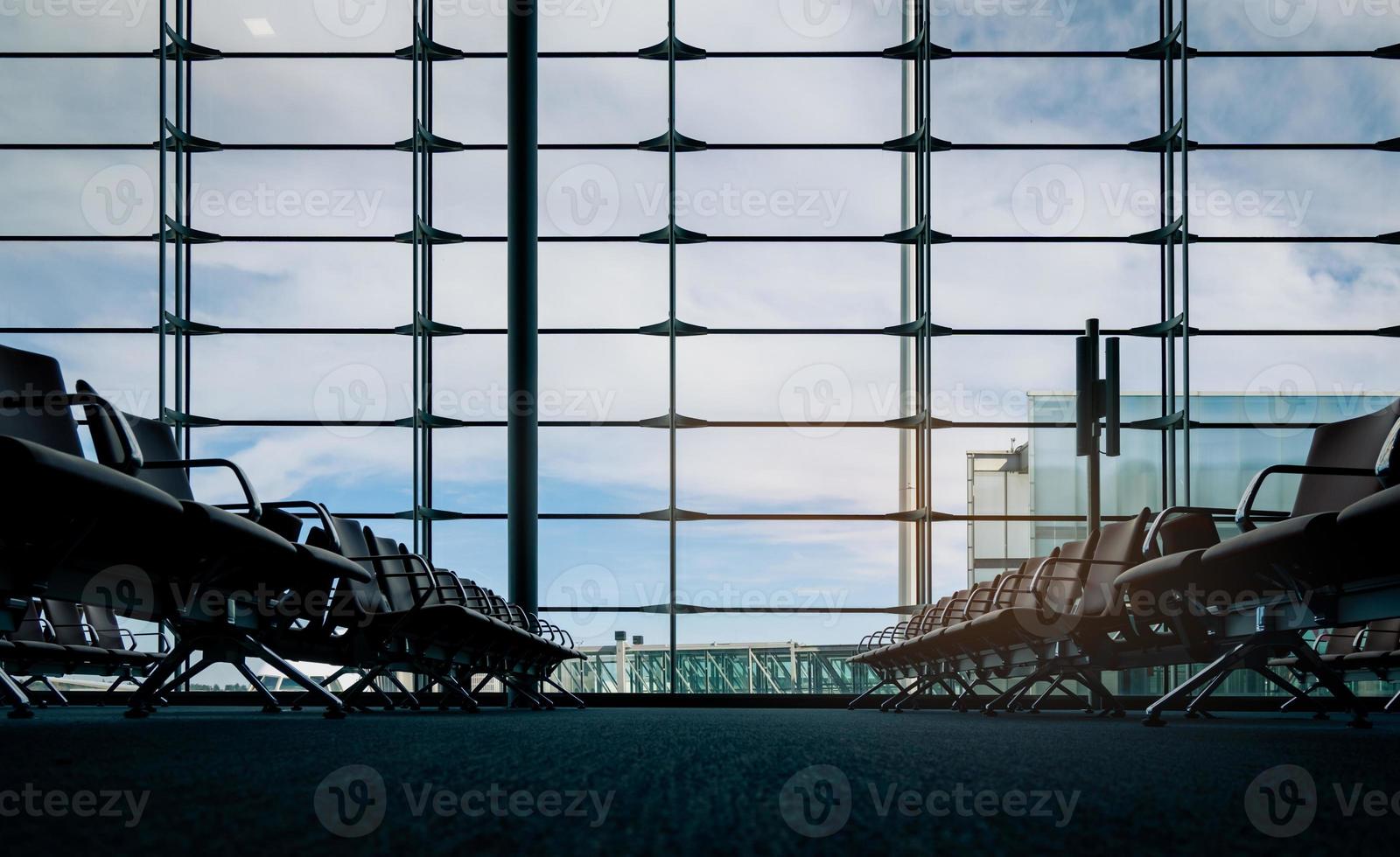 asientos de pasajeros en la sala de embarque en la terminal del aeropuerto. interior de la terminal del aeropuerto. sillas en el área de salida en la puerta internacional. negocios de transporte y viajes. asiento vacío para el vuelo en espera. foto