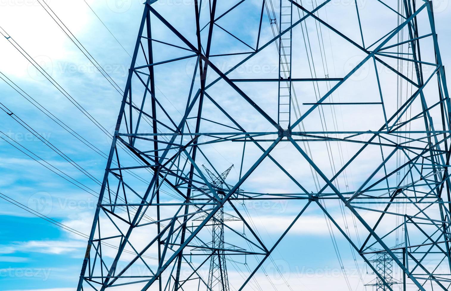 High voltage electric tower and transmission lines. Electricity pylons with blue sky and white clouds. Power and energy conservation. High voltage grid tower with wire cable at distribution station. photo