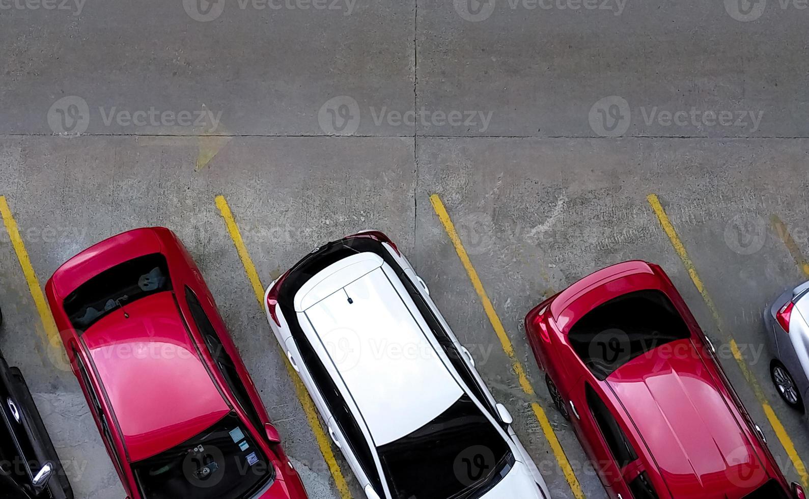 Top view of car parked at concrete car parking lot with yellow line of traffic sign on the street. Above view of car in a row at parking space. No available parking slot. Outside car parking area. photo