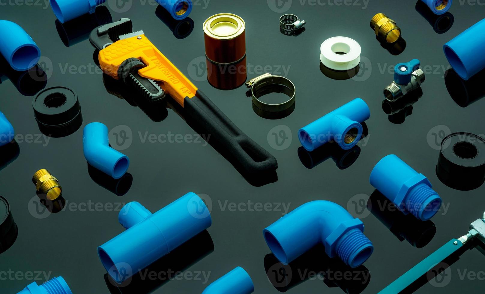 Plumbing tools. Plumber equipment. Blue PVC pipe fittings, glue can, and monkey pipe wrench. House plumbing repair and maintenance service. DIY tools for plumbing work isolated on dark background. photo