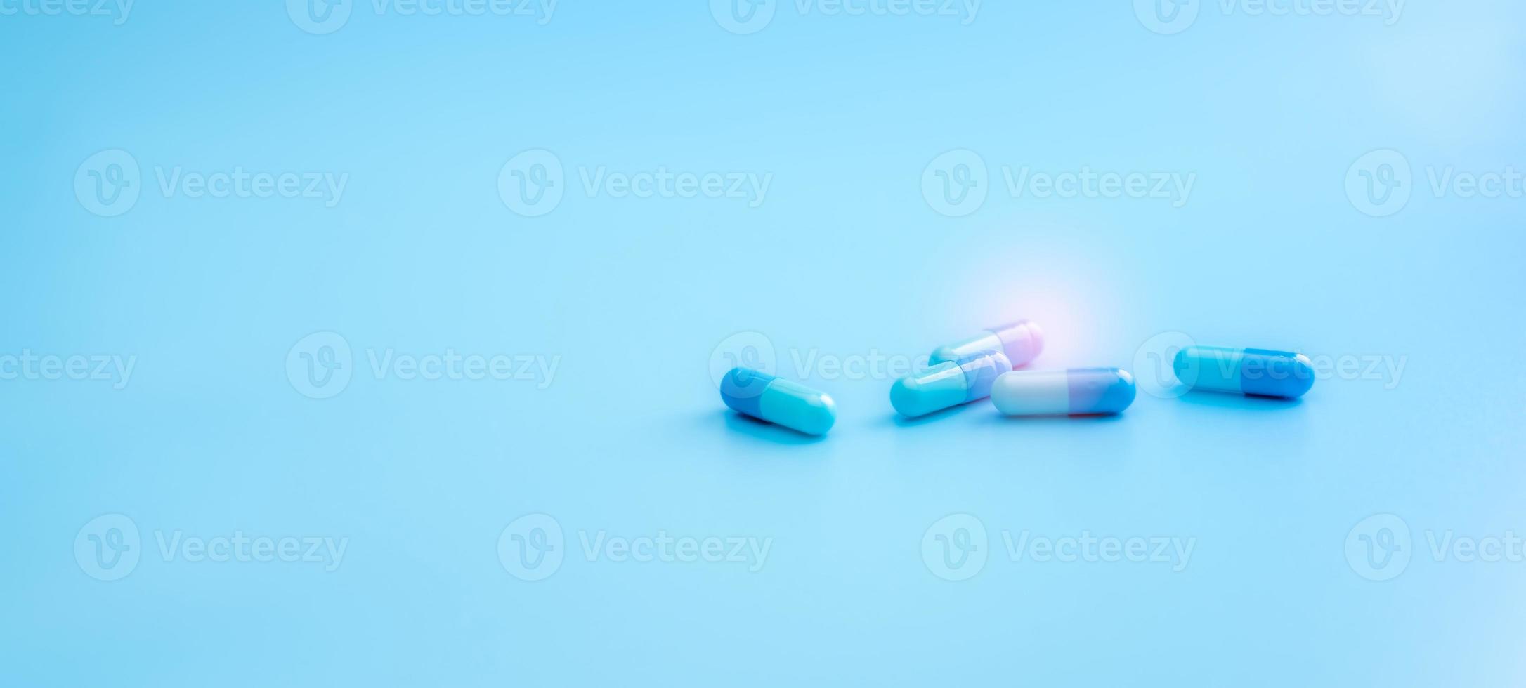 Blue capsule pills on blue background. Pharmacy shop banner. Healthcare and medicine. Pharmaceutical industry. Drug research and development for treatment coronavirus infection. Antiviral medicine. photo
