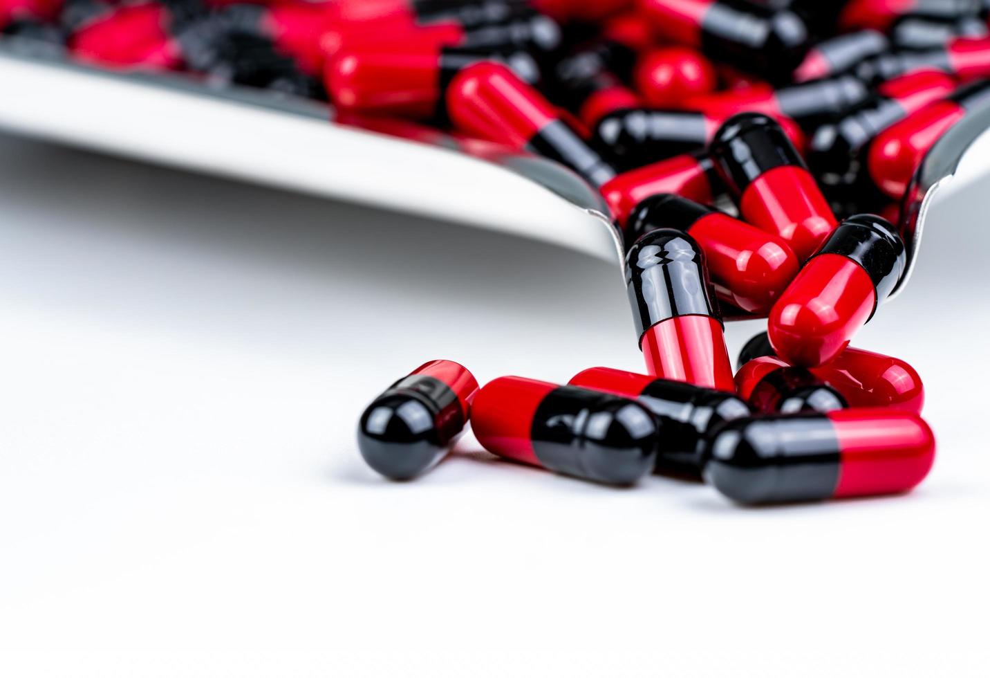 Selective focus of red and black capsule pills on stainless steel drug tray. Antibiotics drug resistance. Global healthcare. Antimicrobial capsule pills. Pharmacy background. Health budgets and policy photo