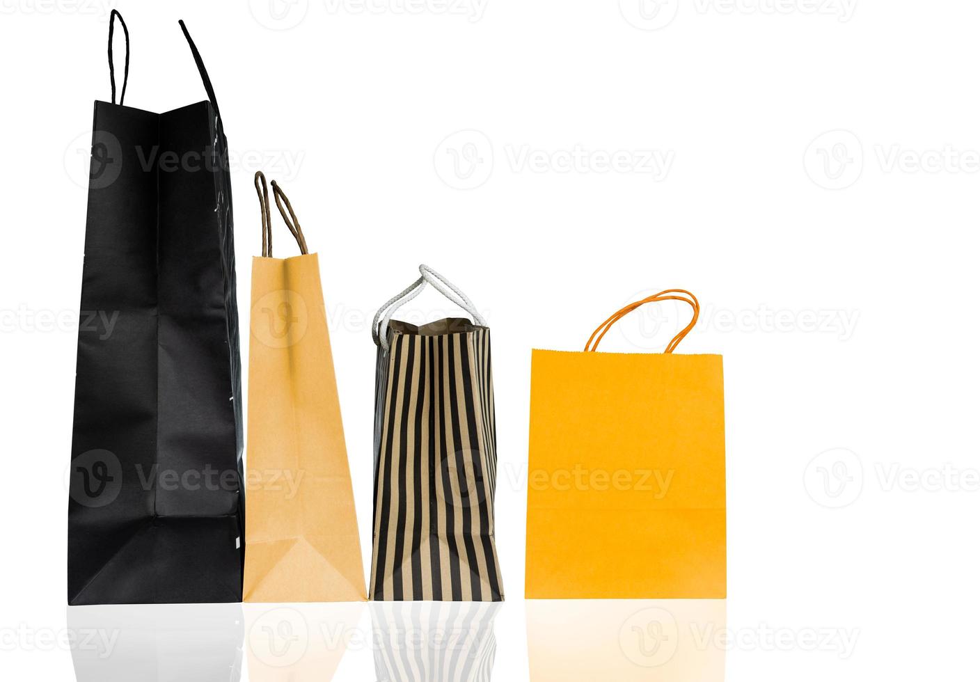 Four paper shopping bags isolated on white background. Shopping bag with blue, brown, and yellow color. Discount sales concept. Gift bag. Consumerism concept. Christmas or New Year present bag. photo