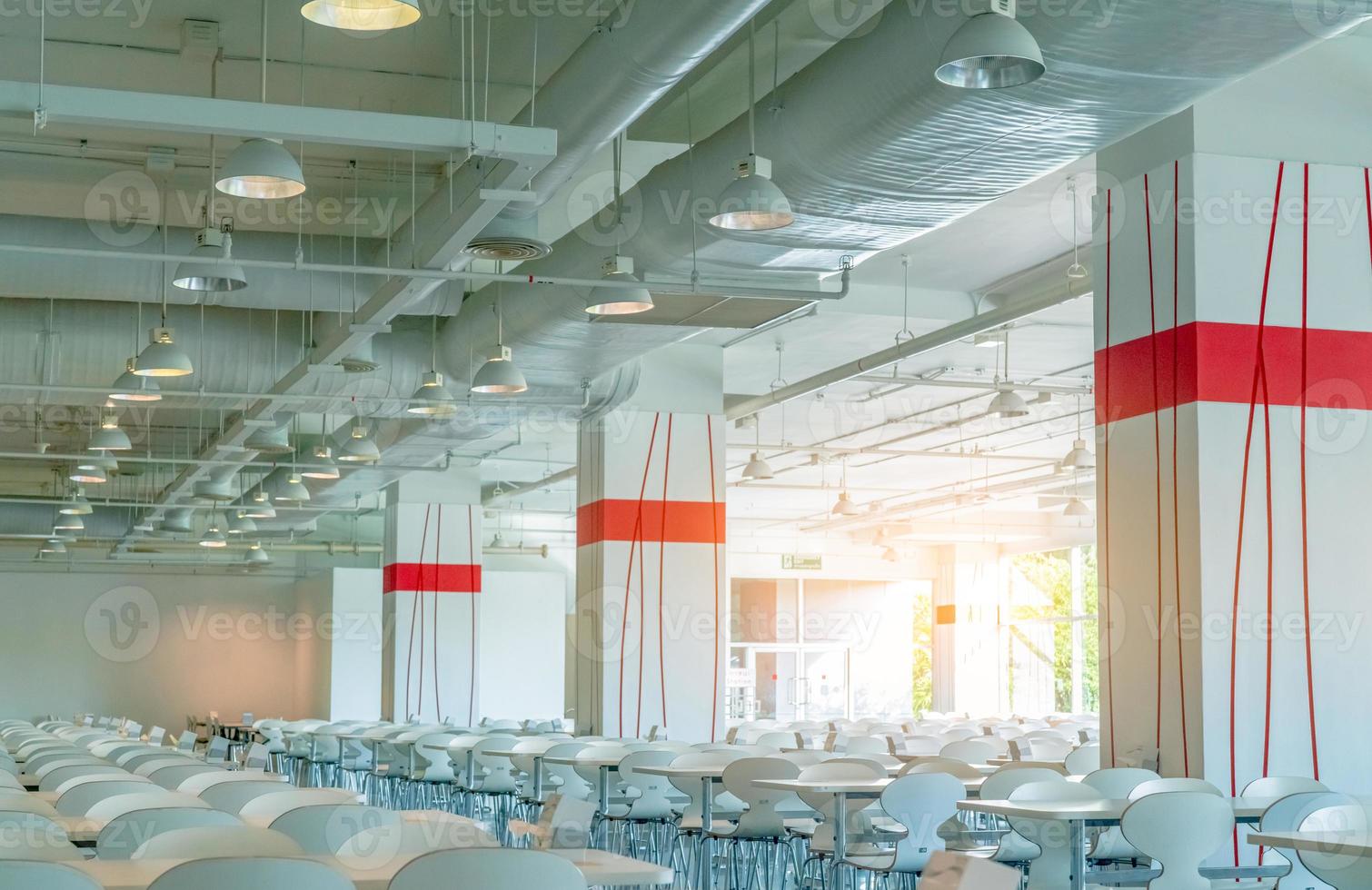 Empty chair and table in the room. Air duct, air conditioner pipe, wiring pipe, and fire sprinkler system. Air flow and ventilation system. Building interior. Ceiling lamp light. Interior architecture photo