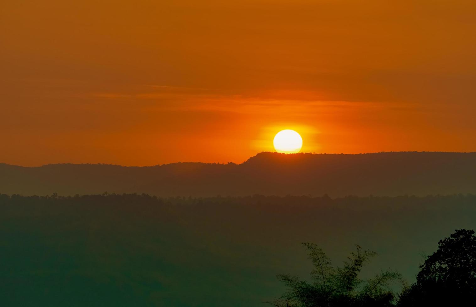 Beautiful nature landscape of mountain with sunset sky and clouds. Scenery of mountain layer at dusk with big round sun. Natural background. Orange and red sky in the evening. Sunset sky background. photo