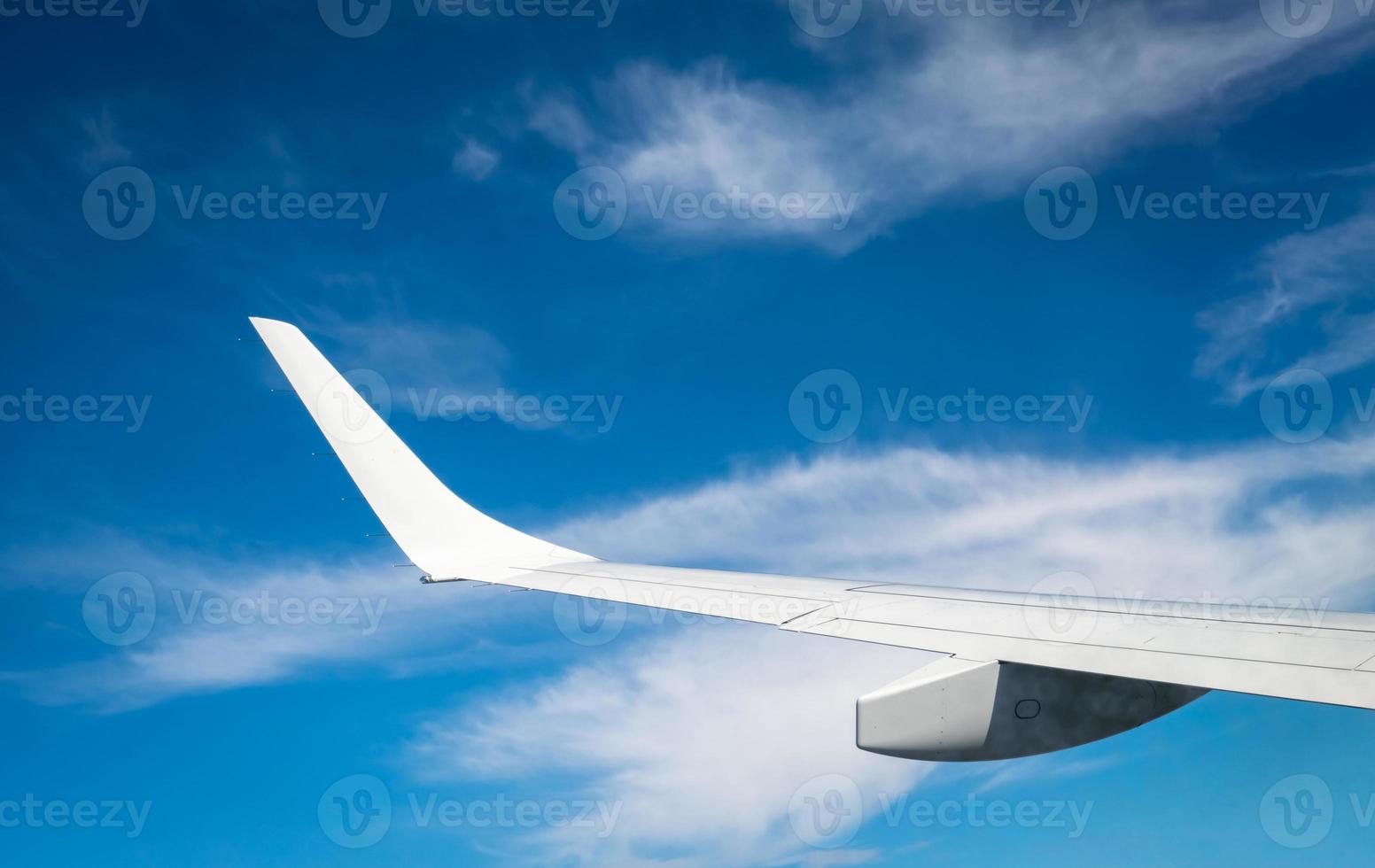 Wing of plane over white clouds. Airplane flying on blue sky. Scenic view from airplane window. Commercial airline flight. Plane wing above clouds. Flight mechanics concept. International flight. photo