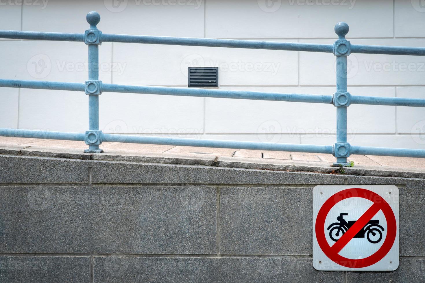 Motorcycle no entry sign install in front of tunnel under the road. Traffic sign to prohibit motorcycle. Restrictive signs. Ramp and iron rail. Motorcycle caution and stop driving to this way. photo