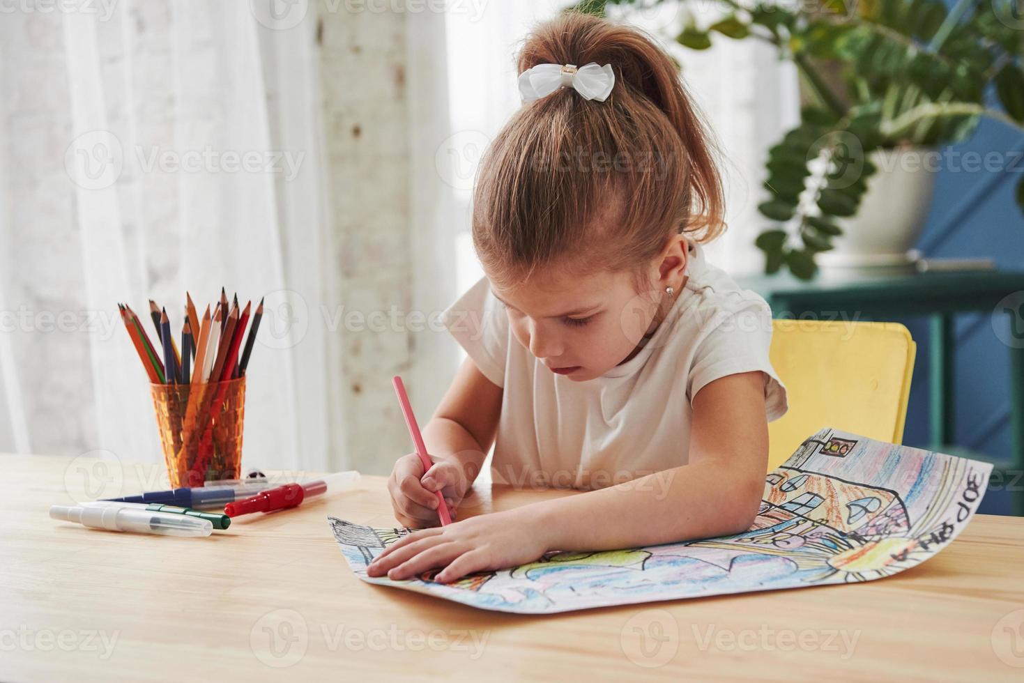 Diligent student. Cute little girl in art school draws her first paintings by pencils and markers photo