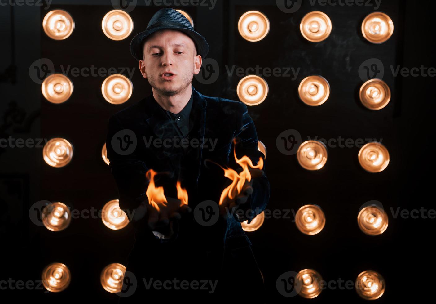 ardiendo bien. ilusionista profesional con sombrero negro, camisa y guantes jugando con fuego foto