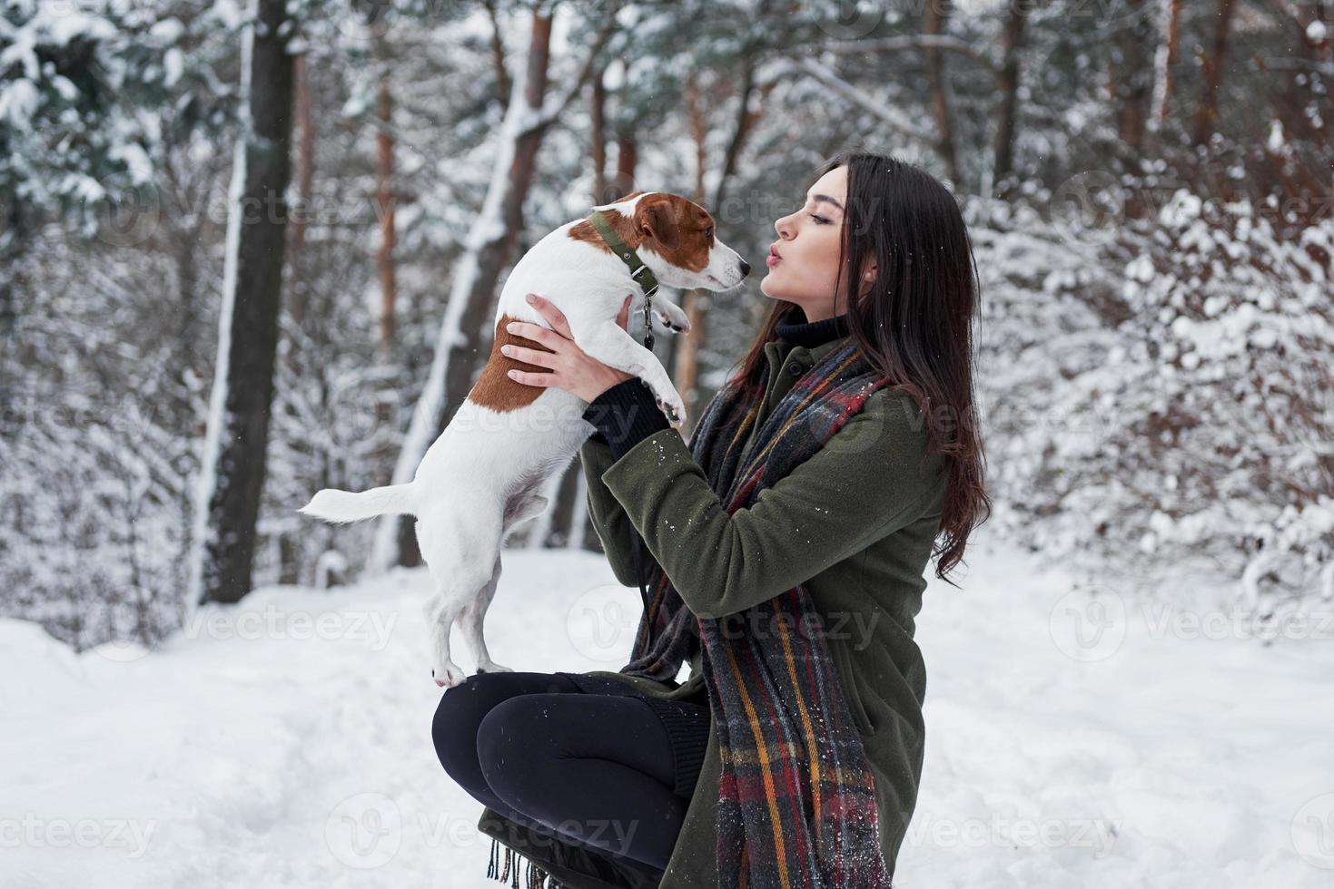 Side view. Smiling brunette having fun while walking with her dog in the winter park photo