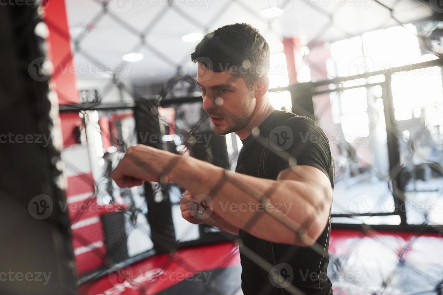 Ready to punch. Strong man is boxing in the gym behind the fence. Haves daily exercise photo