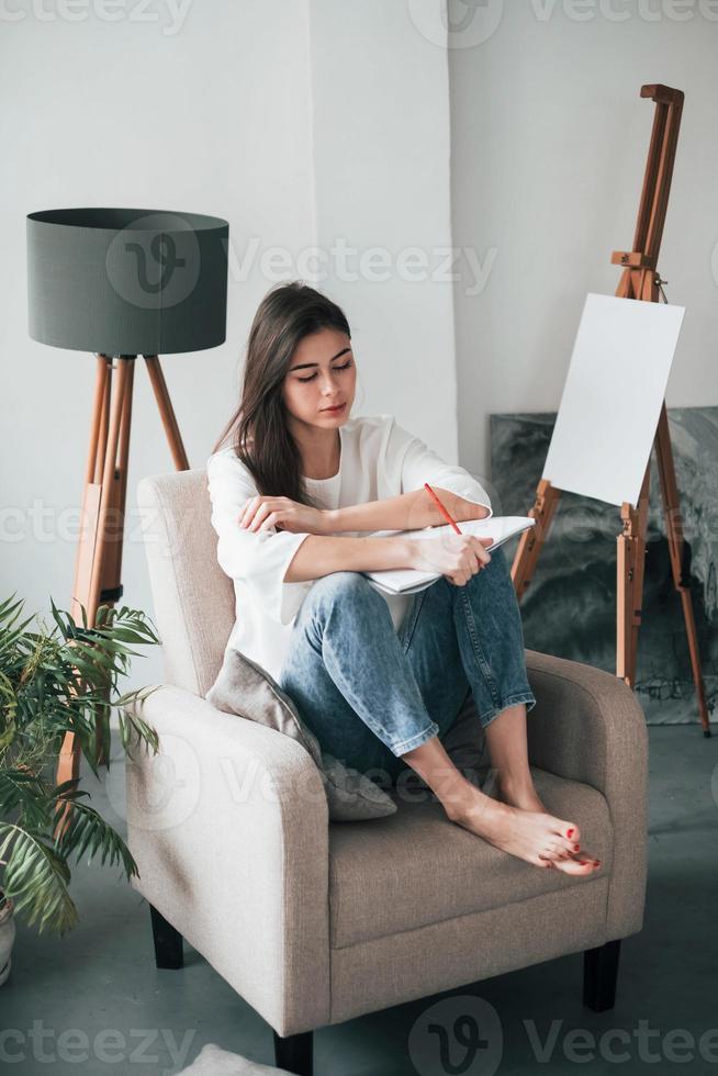 Freedom of mind. Female writer work on new project. Young brunette in the room with white walls and daylight that comes from the window photo