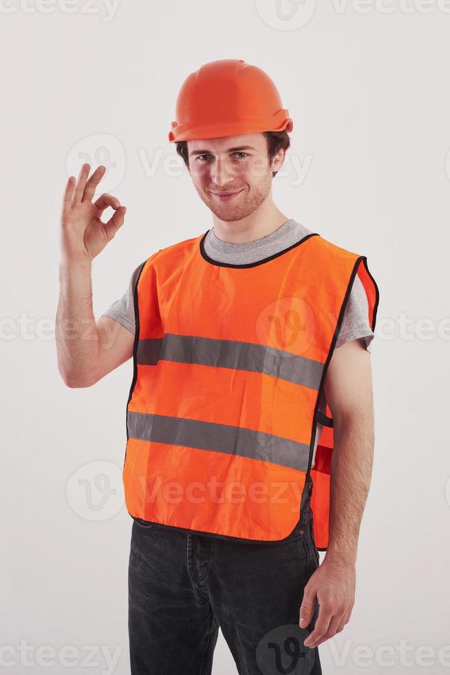 todo estará bien. hombre con uniforme de color naranja se alza contra un fondo blanco en el estudio foto