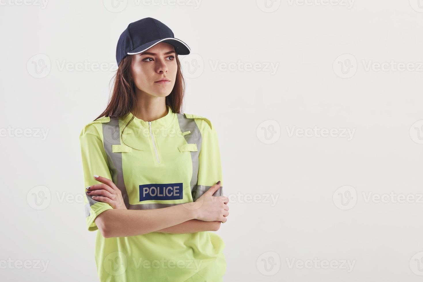 en guardia del orden. una mujer bonita con uniforme de policía verde se alza contra un fondo blanco en el estudio foto