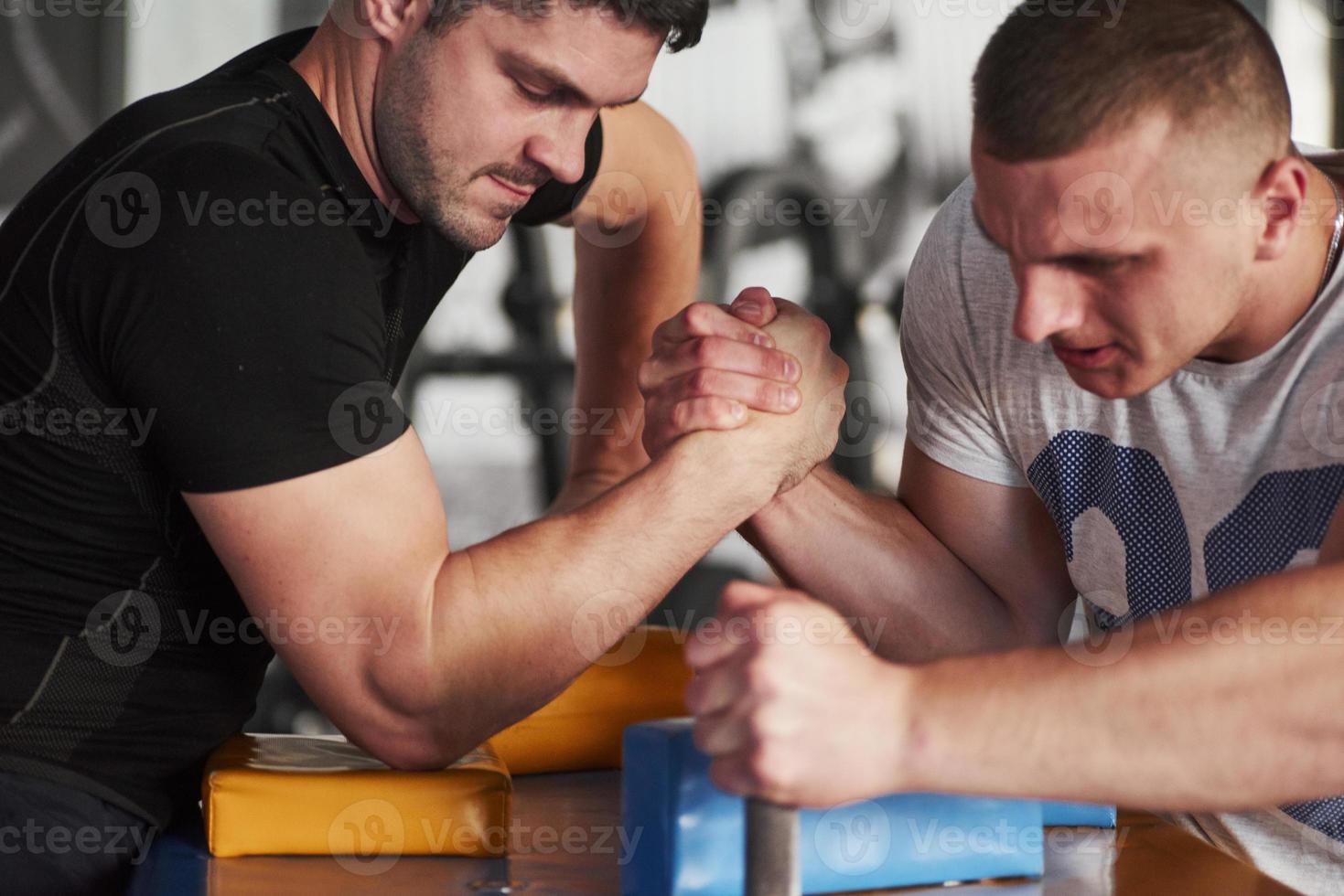 Fully concentrated on the game. Arm wrestling challenge between two men. Match on a special table photo