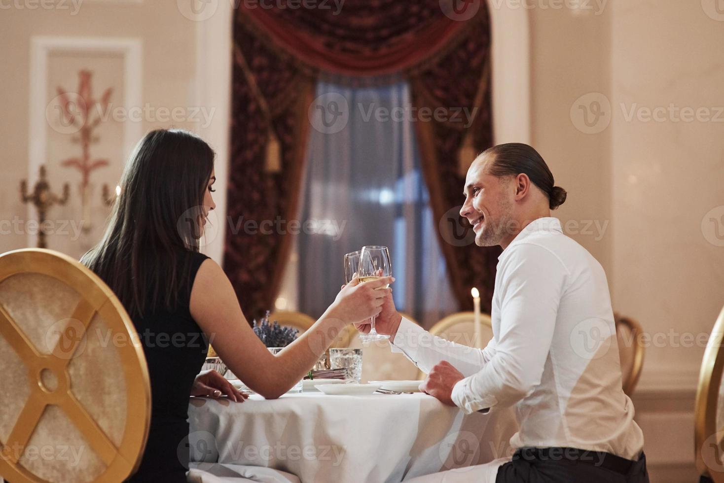 se sienta contra la ventana. una pareja hermosa tiene una cena romántica en un restaurante de lujo por la noche foto