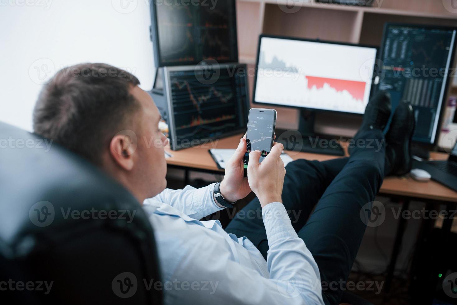 Business owner. Man working online in the office with multiple computer screens in index charts photo