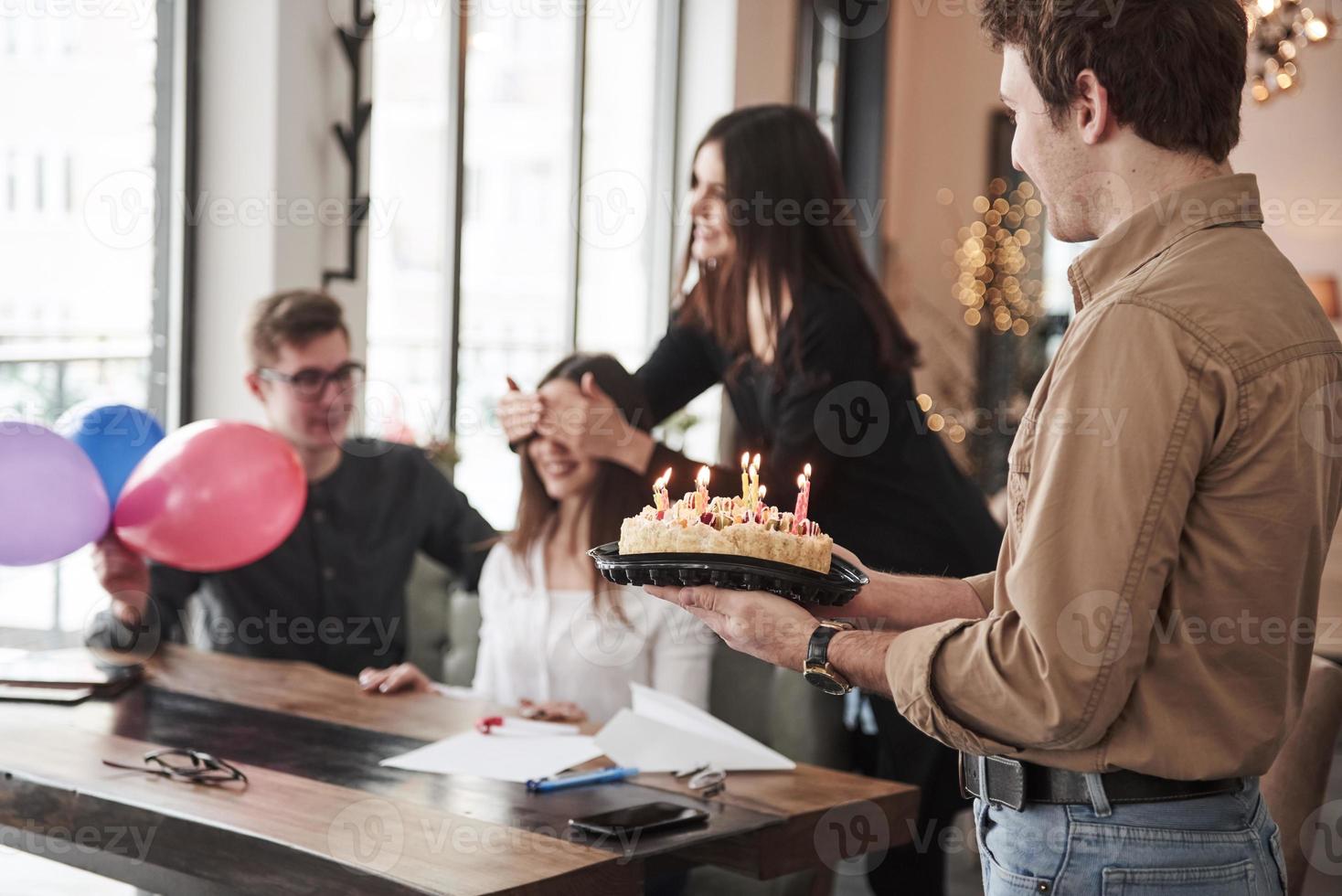 Guy holds cake for the girl. One of employees have birthday today. Friendly coworkers decides to make surprise for her photo