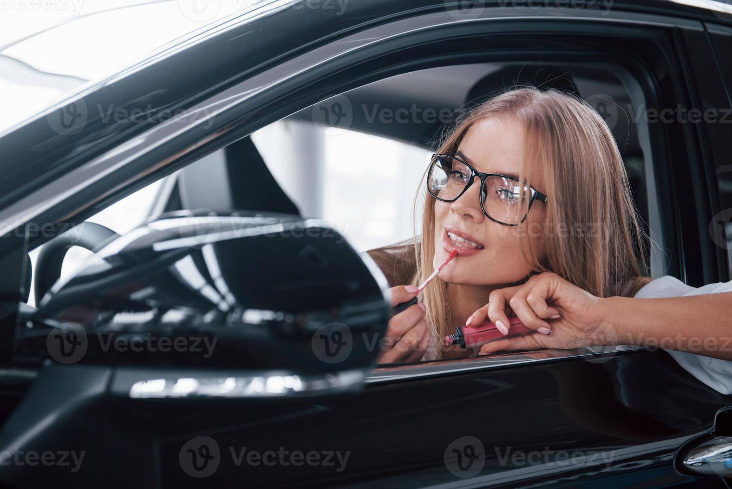 debe verse perfecto. hermosa chica rubia sentada en el auto nuevo con interior negro moderno foto