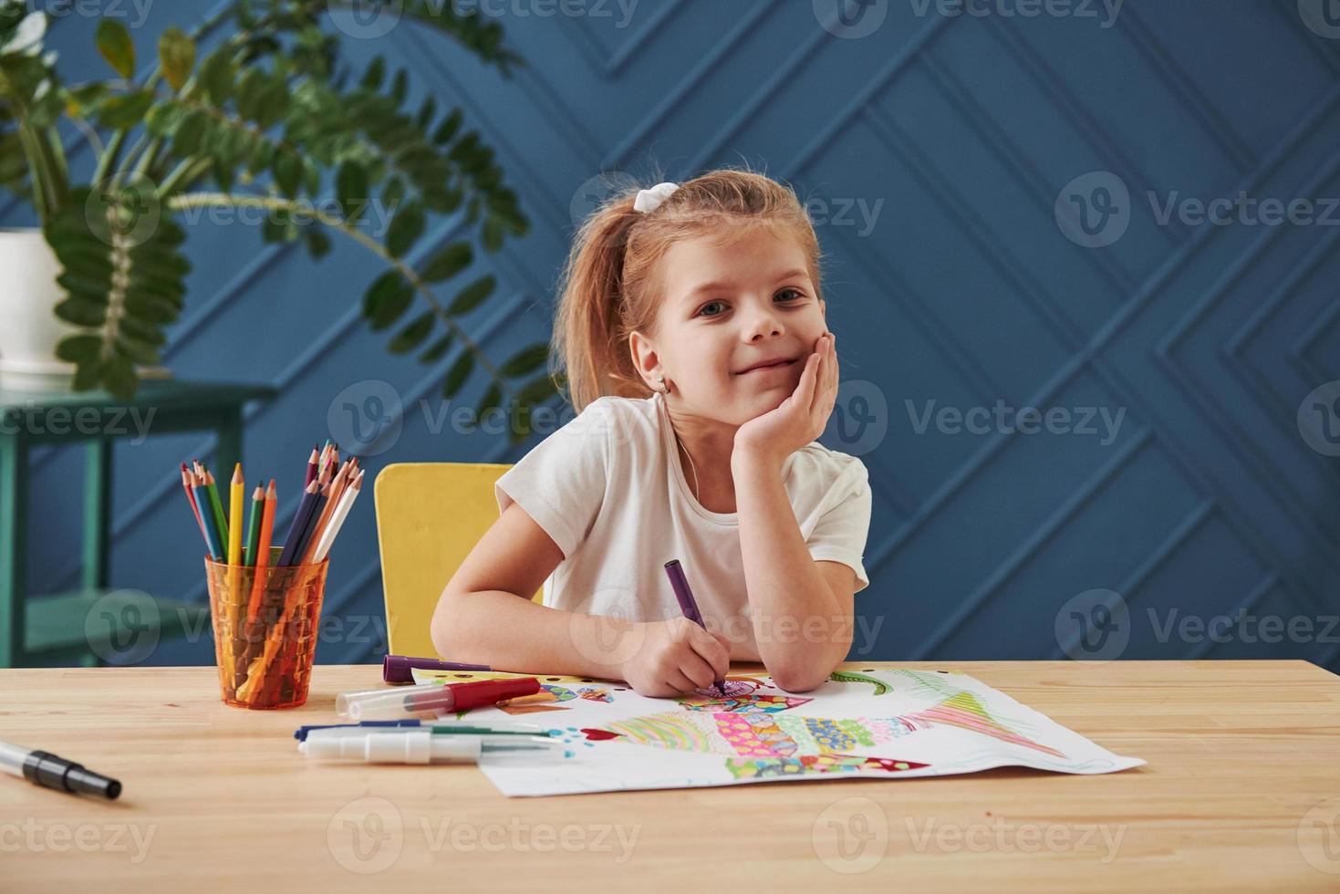 buen retrato linda niña en la escuela de arte dibuja sus primeras pinturas con lápices y marcadores foto