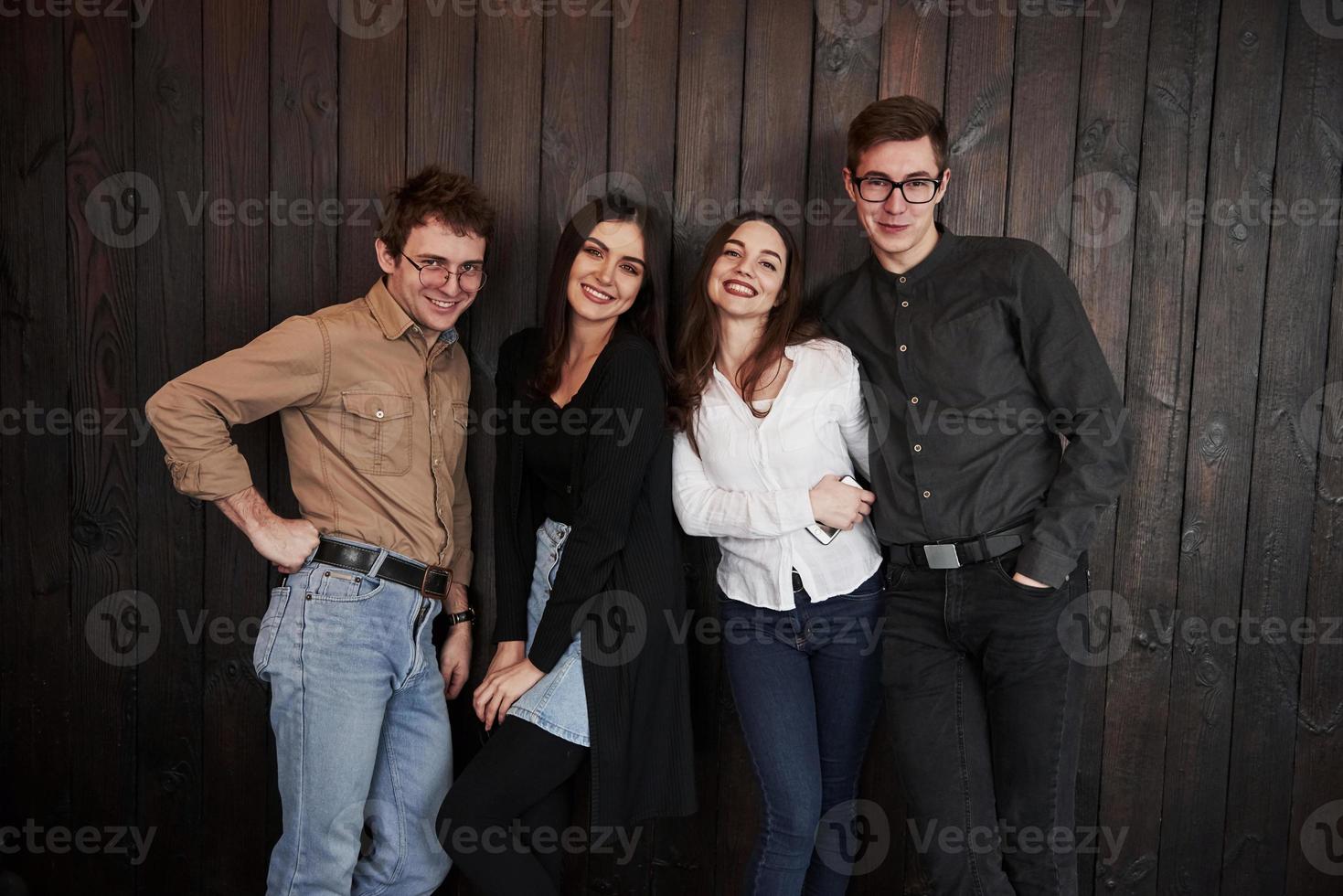 In the restaurant room. Youth stands against black wooden wall. Group of friends spending time together photo