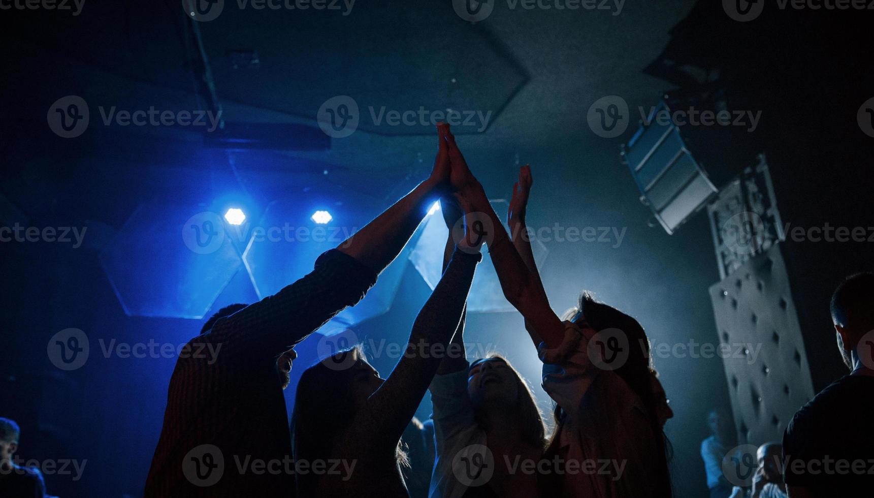 It's high five. Group of people that enjoying dancing in the nightclub with beautiful lightings photo