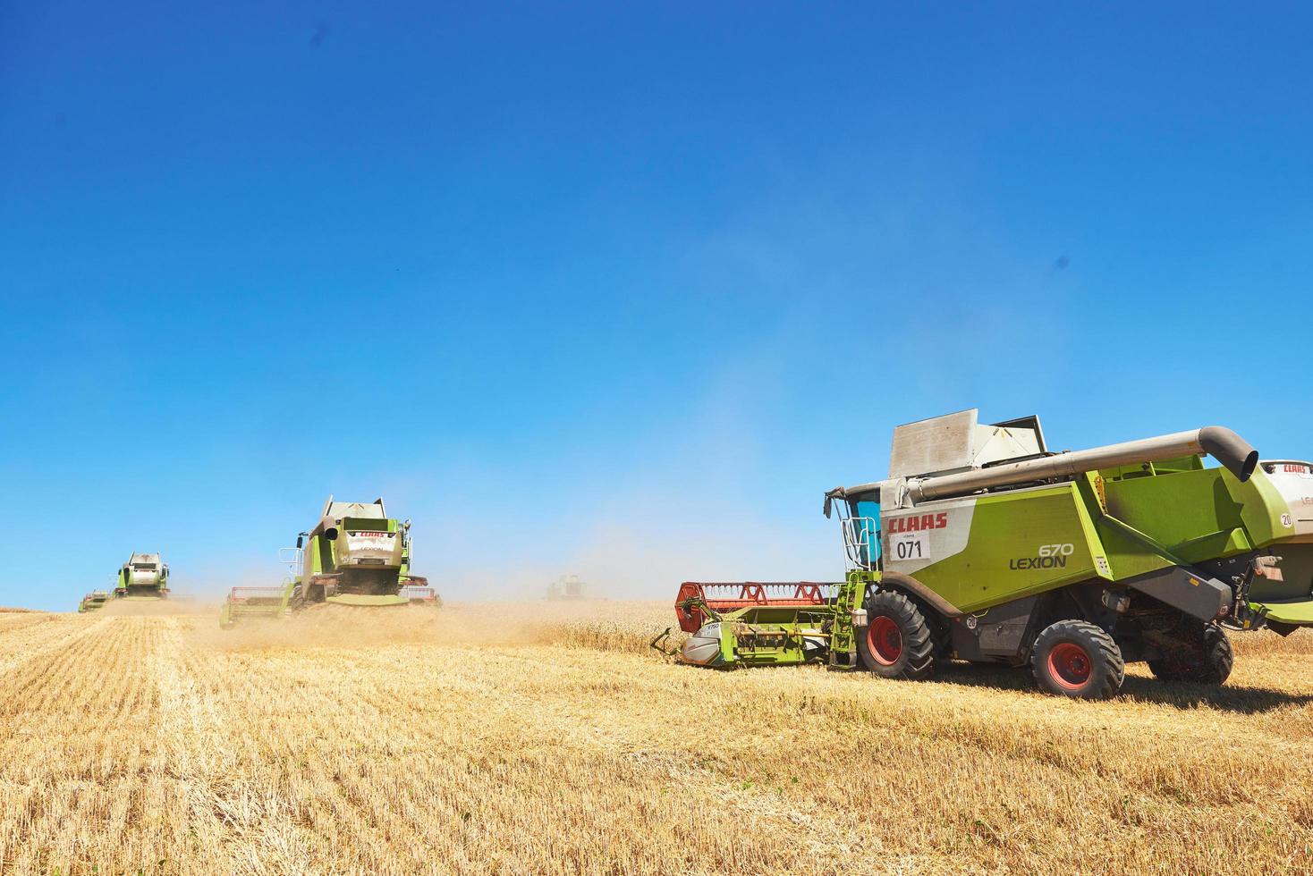 TERNOPIL - JULY 20 A few combines cutting a swath through the middle of a wheat field during harvest on July 20, 2017, in Ternopil photo