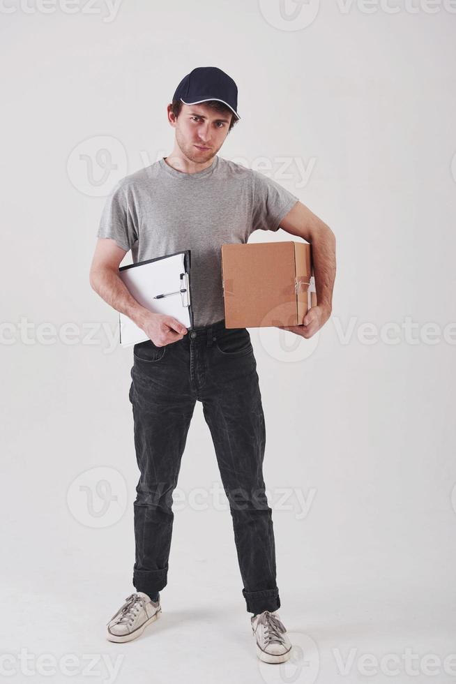 Modern post services. Guy with box in hands stands against white background in the studio photo
