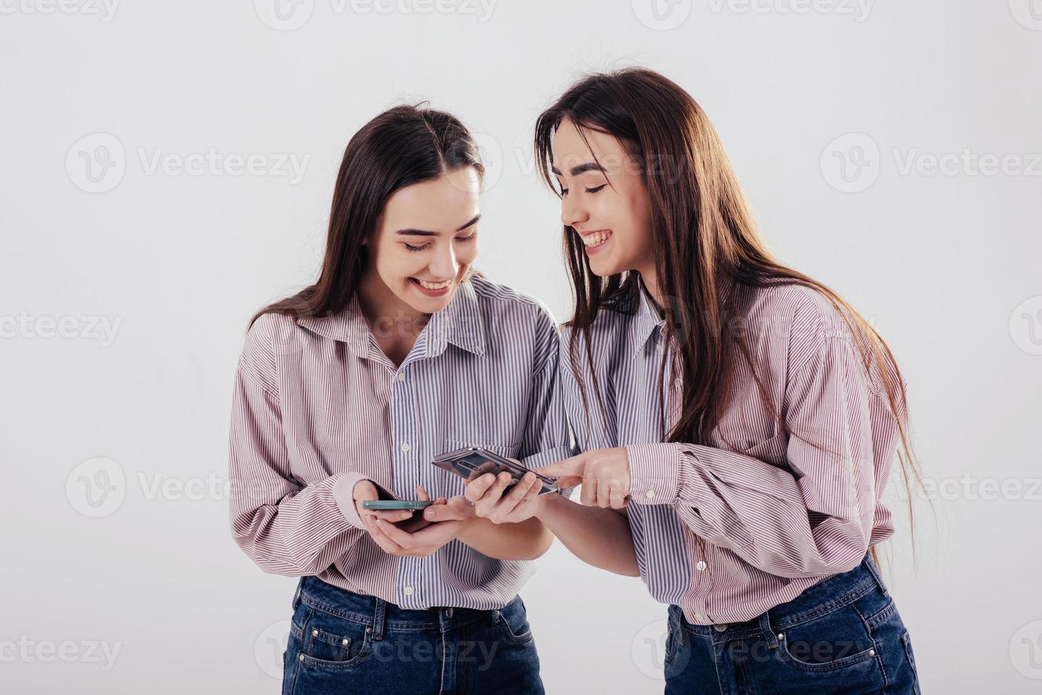 Look at this funny picture. Two sisters twins standing and posing in the studio with white background photo