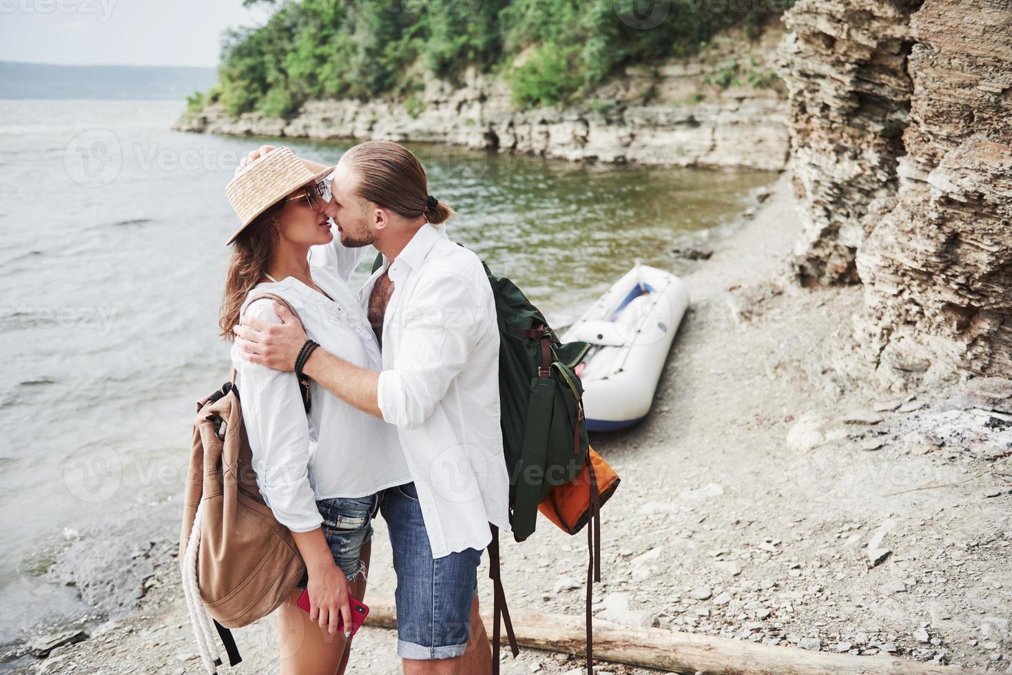 Cute young and couple on river background. A guy and a girl with backpacks are traveling by boat. Traveler summer concept photo