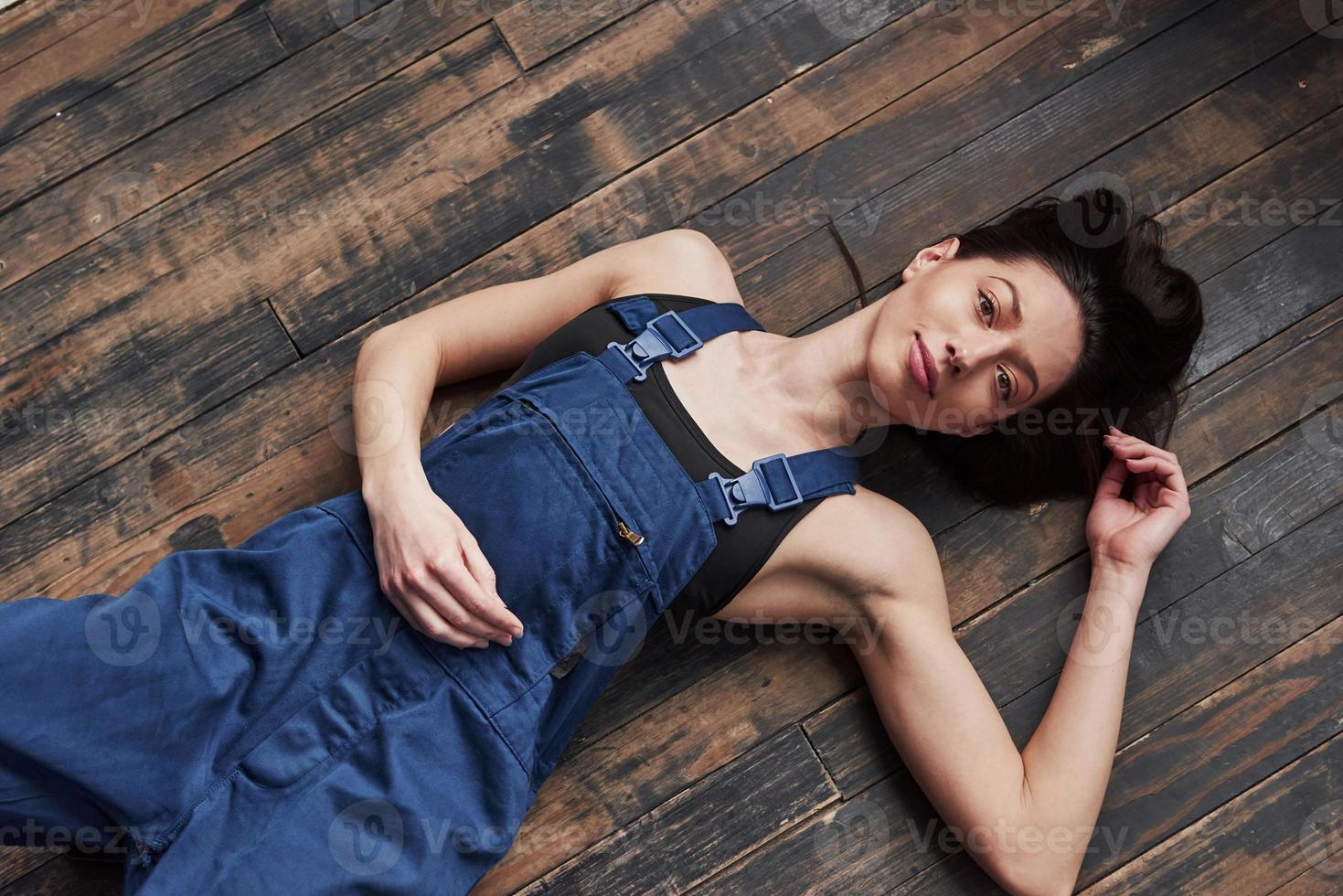Top view. Girl in the blue uniform for the work is lying on wooden floor having relax photo