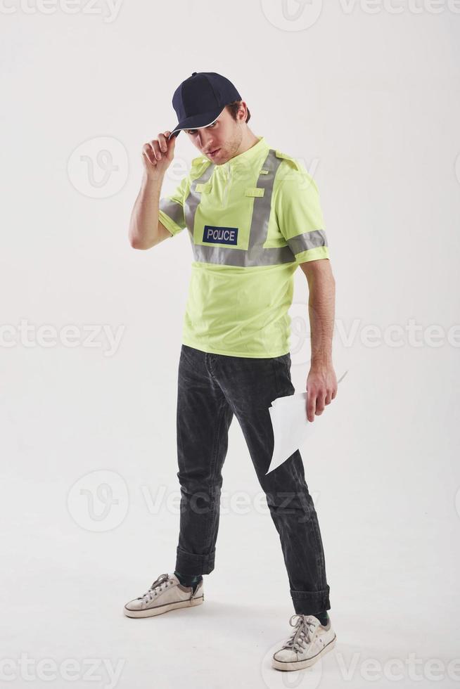 Some documents in the hand. Policeman in green uniform stands against white background in the studio photo